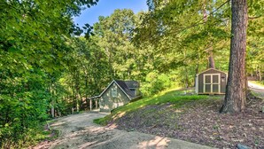 Un chalet isolé, entouré d’une forêt dense, avec un chemin de terre menant à une petite maison.
