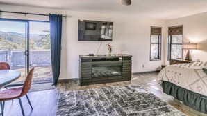 A bedroom with a large bed, a ceiling fan, a TV, and a view of the outdoors. - Cozy Studio w/ Well-being Retreat: Near Yosemite! (Ahwahnee)