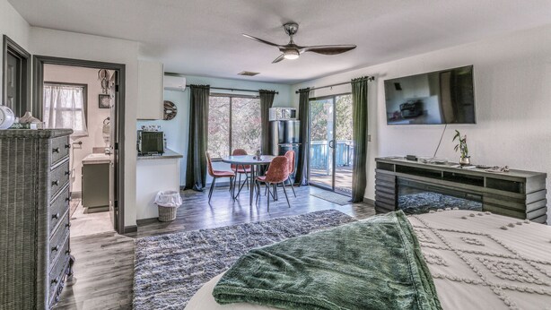 A bedroom with a bed, a desk, a TV, and a balcony with a table and chairs. - Cozy Studio w/ Well-being Retreat: Near Yosemite! (Ahwahnee)