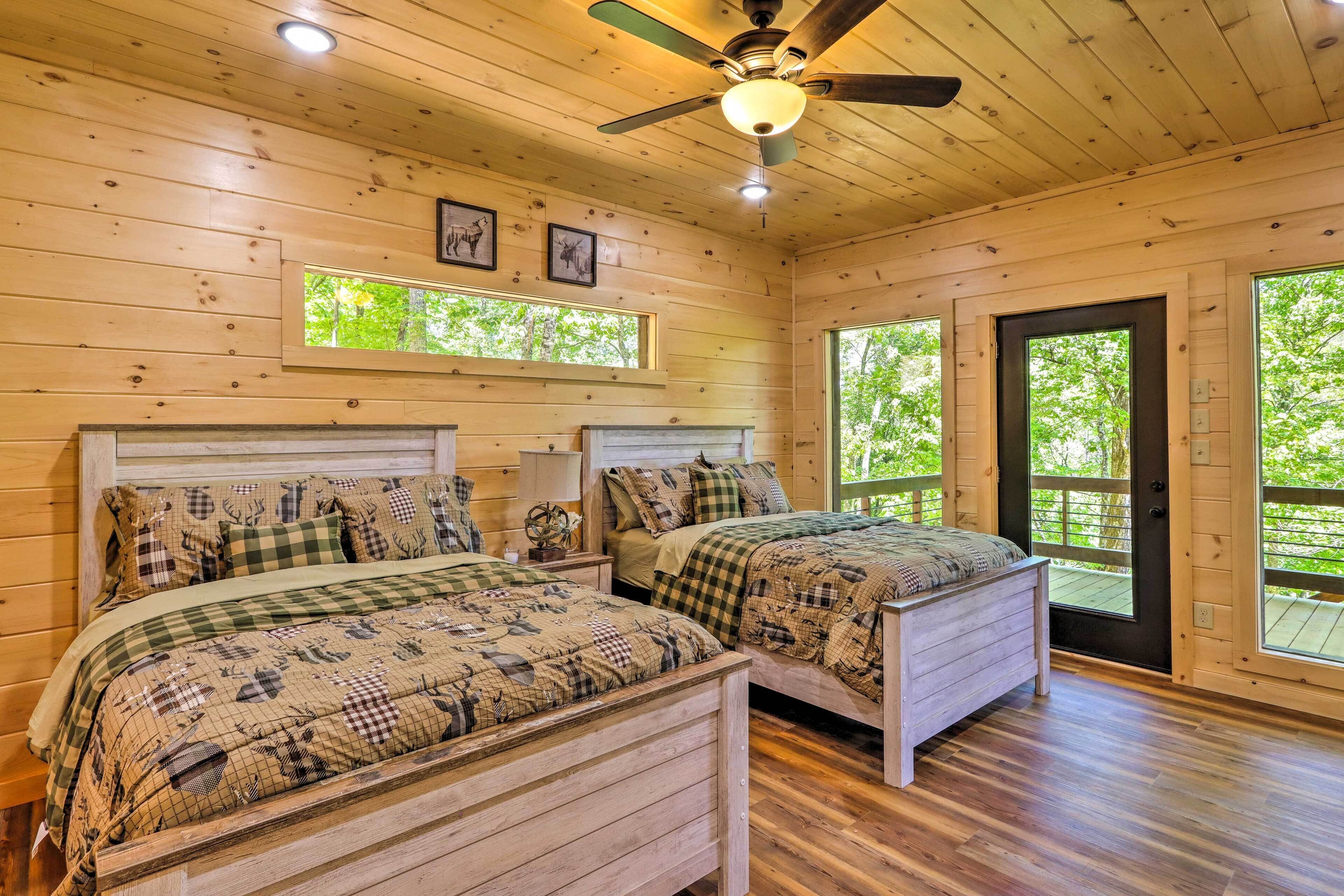 A cabin with two wooden beds, a ceiling fan, and large windows.