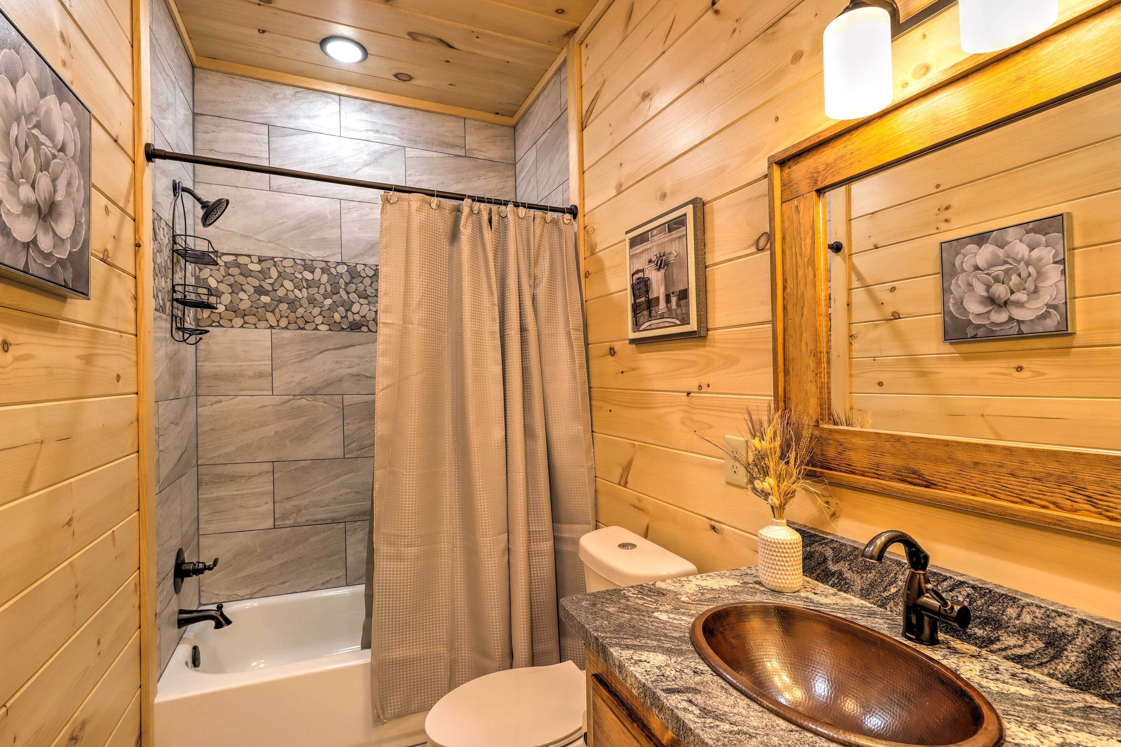 A wooden cabin bathroom with a bathtub, toilet, and a wooden sink.