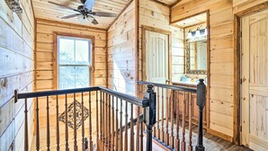 Un intérieur en bois avec un escalier, un ventilateur de plafond et une grande fenêtre.