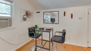 A modern living room with a dining area, a large mirror, and a window with blinds.