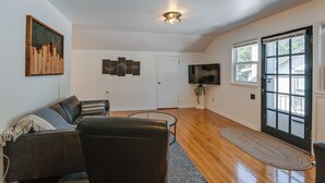 A modern living room with a leather sofa, a flat-screen TV, and artwork on the walls.