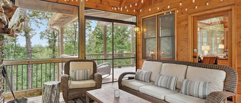 A wooden deck with wicker furniture, a metal bucket, and a glass railing.
