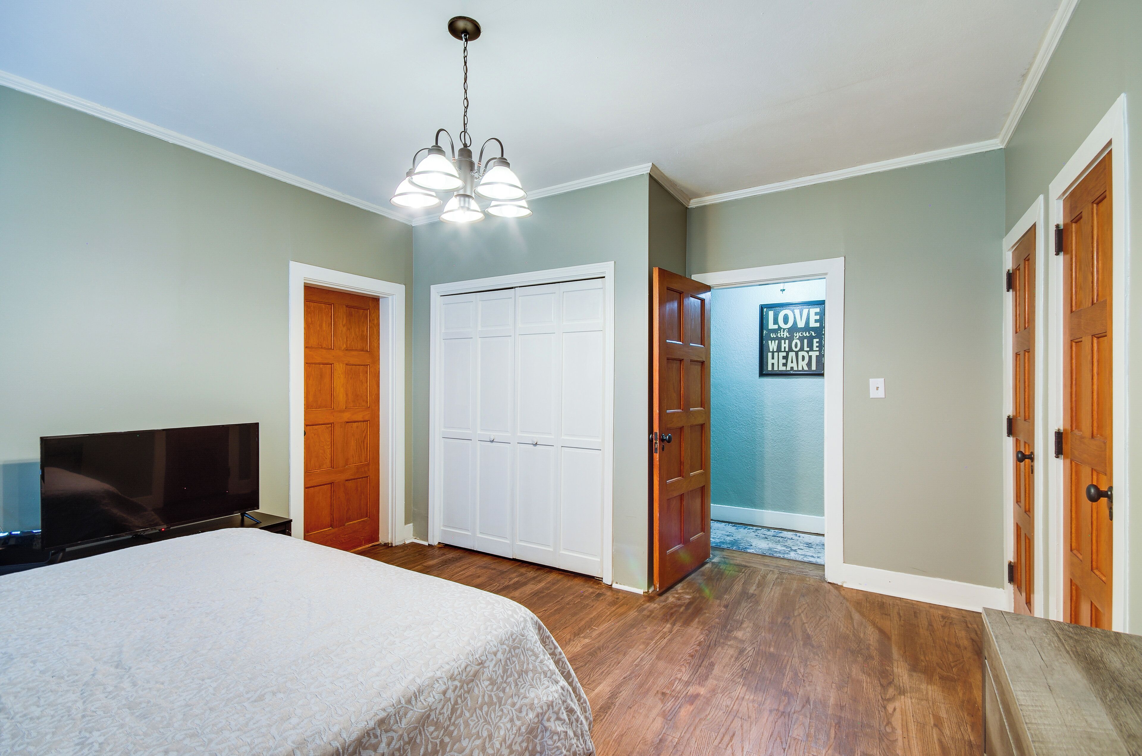 A bedroom with a bed, a TV, a wardrobe, and a door with a motivational poster.