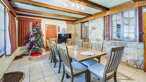 A dining area with a stone wall, wooden ceiling beams, a Christmas tree, and a television. - Cozy Jackson Vacation Rental < 1 Mi to University (Jackson)