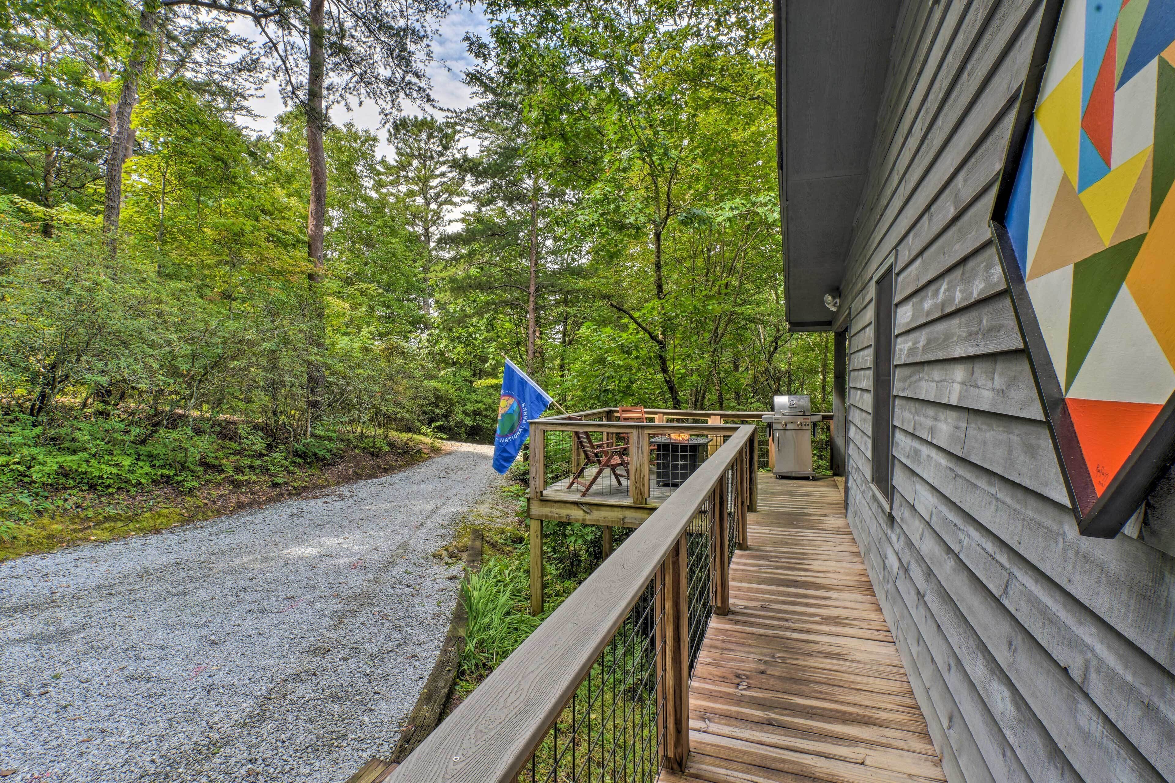 A wooden deck with a railing, a gravel path, and a flag.
