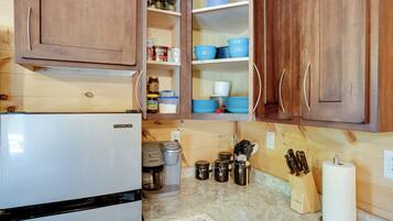 A kitchen with wooden cabinets, a white refrigerator, a coffee maker, and various kitchen utensils.