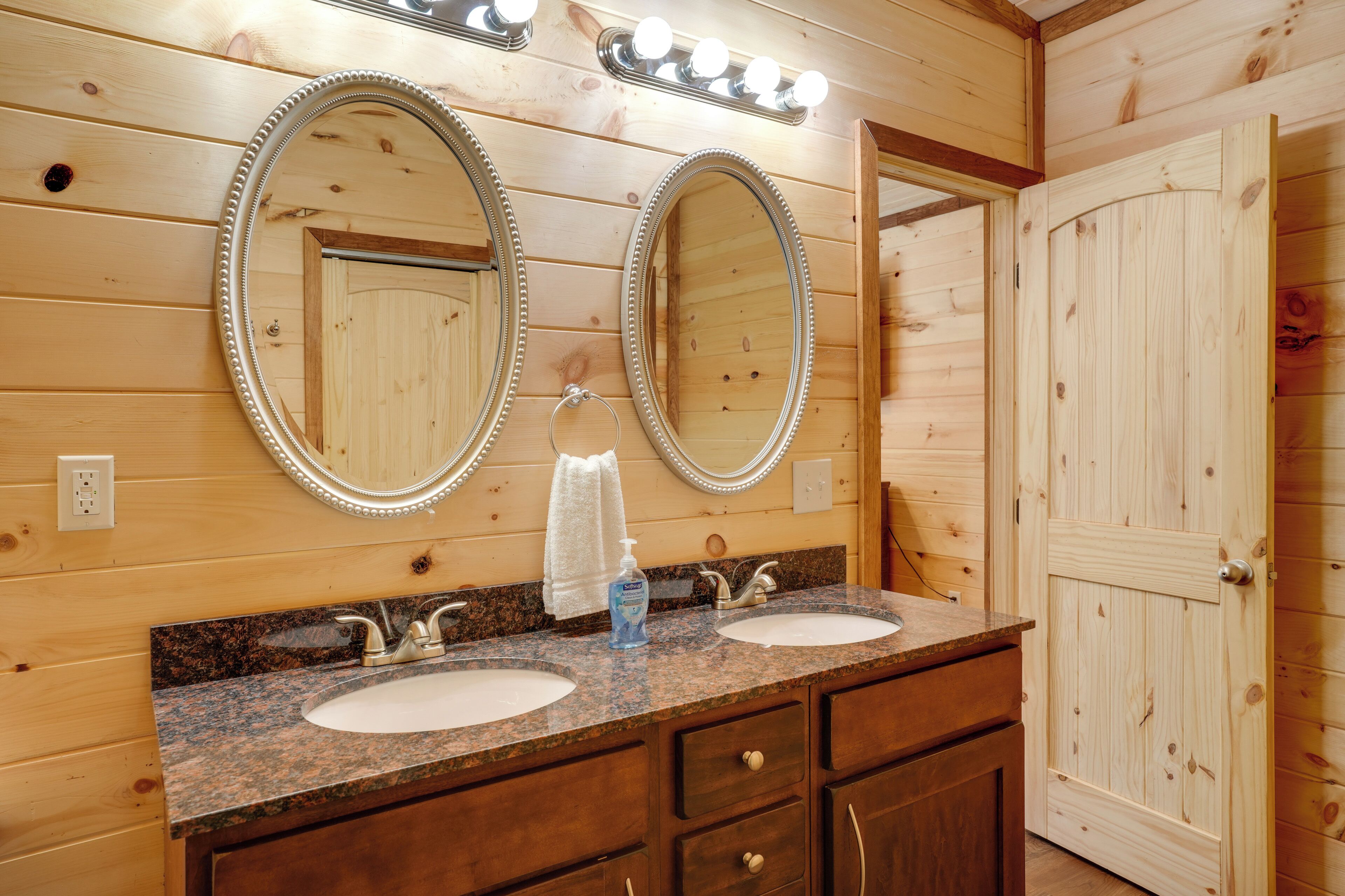 Un baño de cabaña de madera con dos lavamanos, un tocador y una puerta.