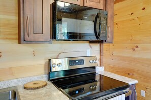 Una cucina con mobili in legno, un forno a microonde in acciaio inossidabile e un forno nero.
