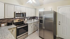 A kitchen with white cabinets, stainless steel appliances, a granite countertop, and a ceiling fan. - Savannah Home w/ Patio & Grill ~ 2 Mi to Downtown (Savannah)