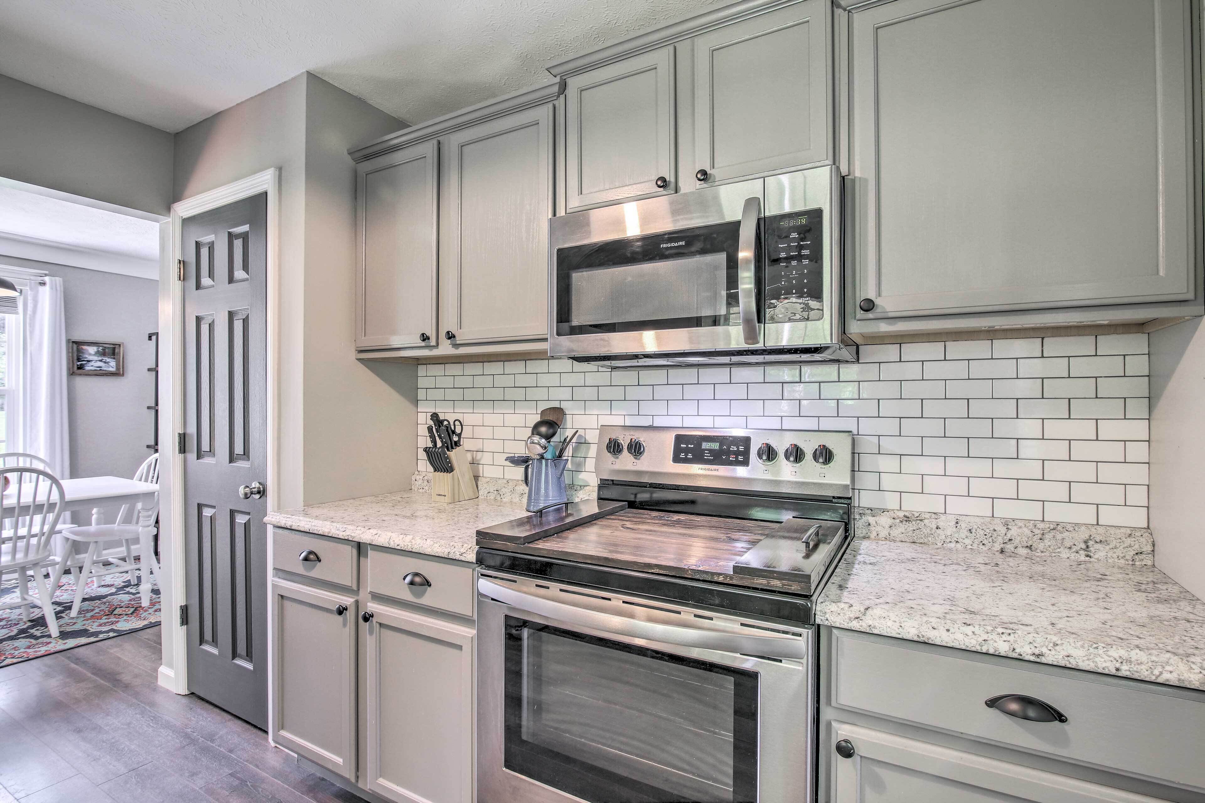 A kitchen with stainless steel appliances, white cabinets, and a tiled backsplash.