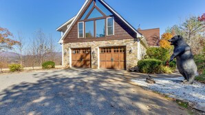 A two-story house with a stone facade, a gabled roof, and a garage with wooden doors.