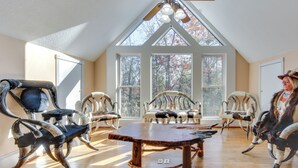 A spacious room with a high ceiling, large windows, and a wooden table in the center.