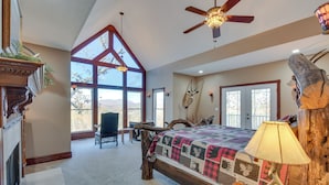 A spacious bedroom with a large bed, a ceiling fan, and a view of the outdoors.