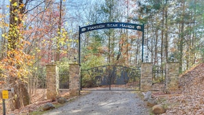 A gated entrance to a property named "Mansion Bear Manor" with a gravel path leading through a wooded area.