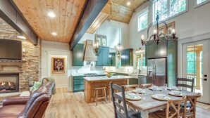 A spacious kitchen with a central island, wooden cabinets, and a large refrigerator. - Luxurious Clarkesville Cabin w/ Decks & Fire Pit (Clarkesville)