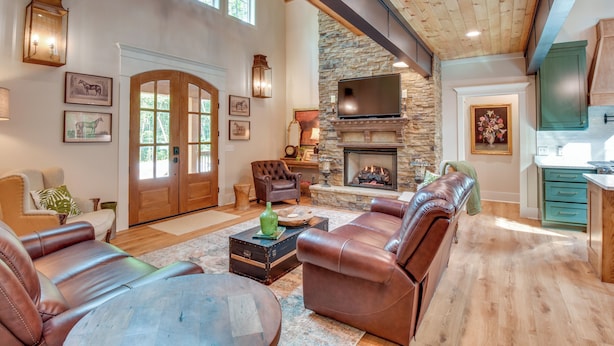 A spacious living room with leather sofas, a stone fireplace, and a television. - Luxurious Clarkesville Cabin w/ Decks & Fire Pit (Clarkesville)