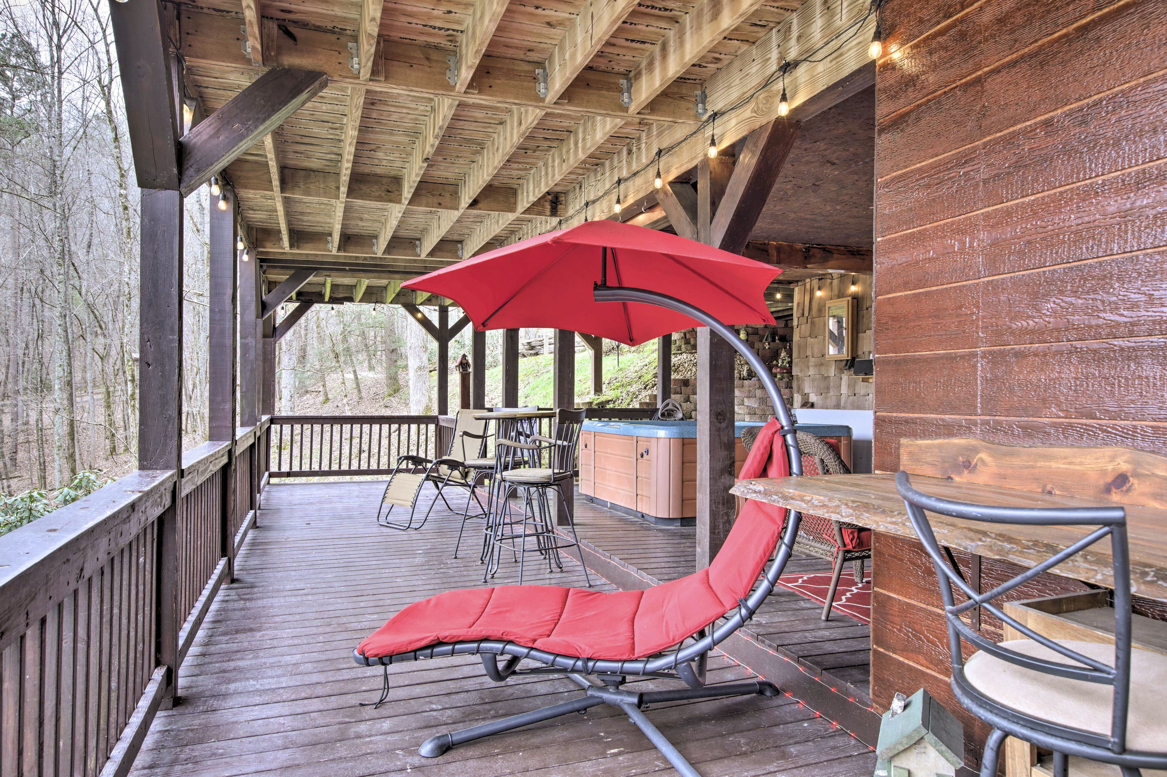A covered outdoor seating area with a red umbrella, wooden deck, and metal chairs.