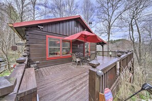 Eine Holzterrasse mit Sitzgelegenheiten im Freien und einem roten Sonnensegel.