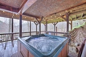 Un jacuzzi bajo una pérgola de madera con vista a árboles.