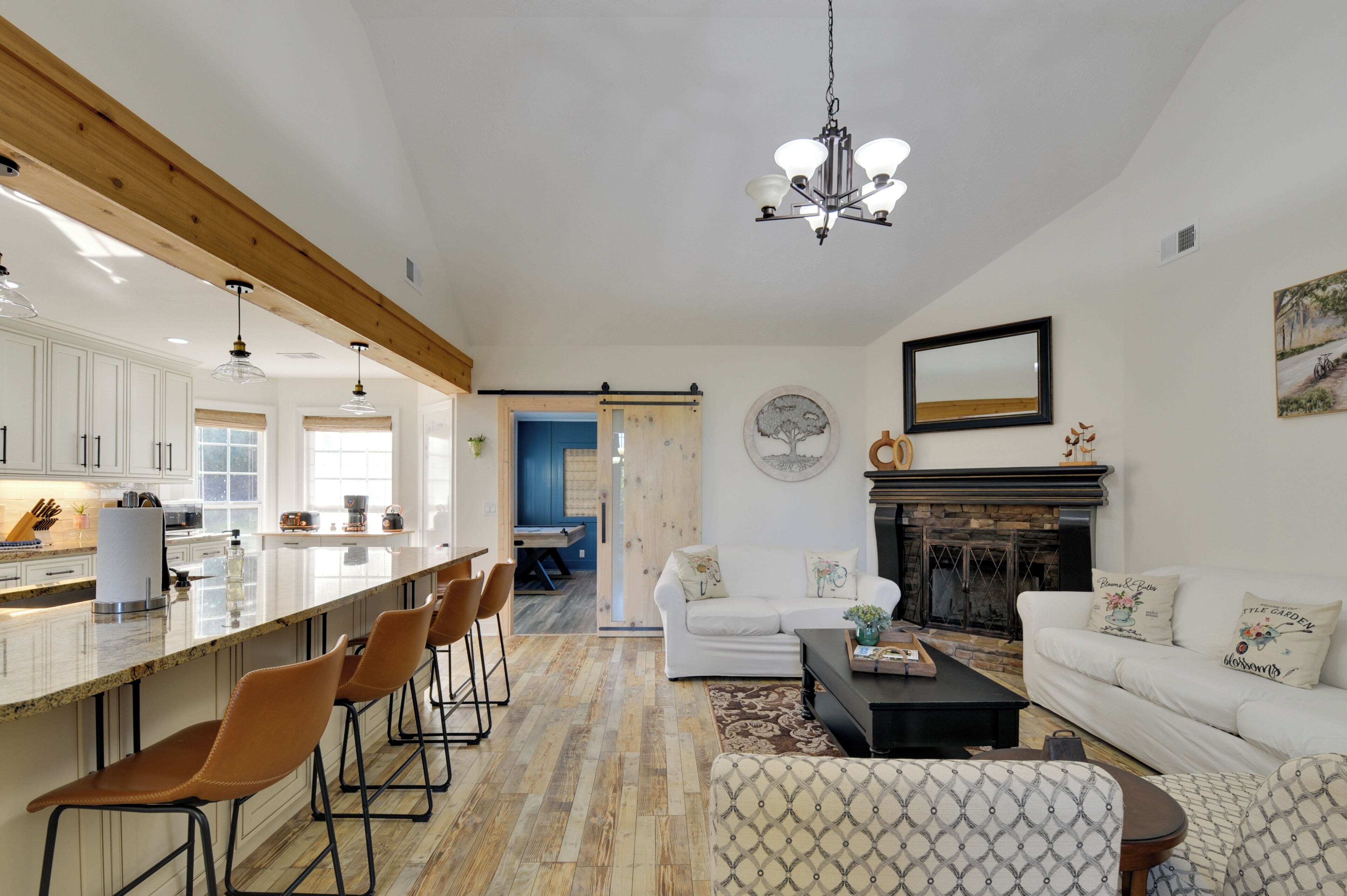 Amplia sala de estar con cocina, chimenea y comedor con taburetes de bar.
