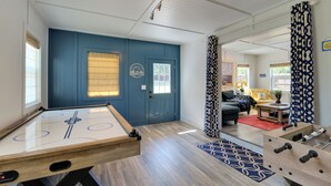 A room with a foosball table, a door with a window, and a living area with a sofa and a coffee table. - Spacious Winder Getaway w/ Hot Tub + Game Room! (Winder)