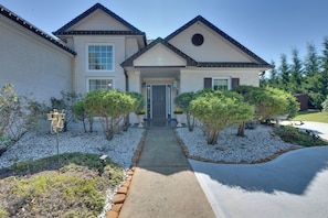 A two-story house with a front porch, a driveway, and a garden with white gravel and shrubs. - Spacious Winder Getaway w/ Hot Tub + Game Room! (Winder)