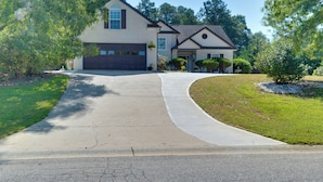 A two-story house with a driveway leading to a garage. - Spacious Winder Getaway w/ Hot Tub + Game Room! (Winder)