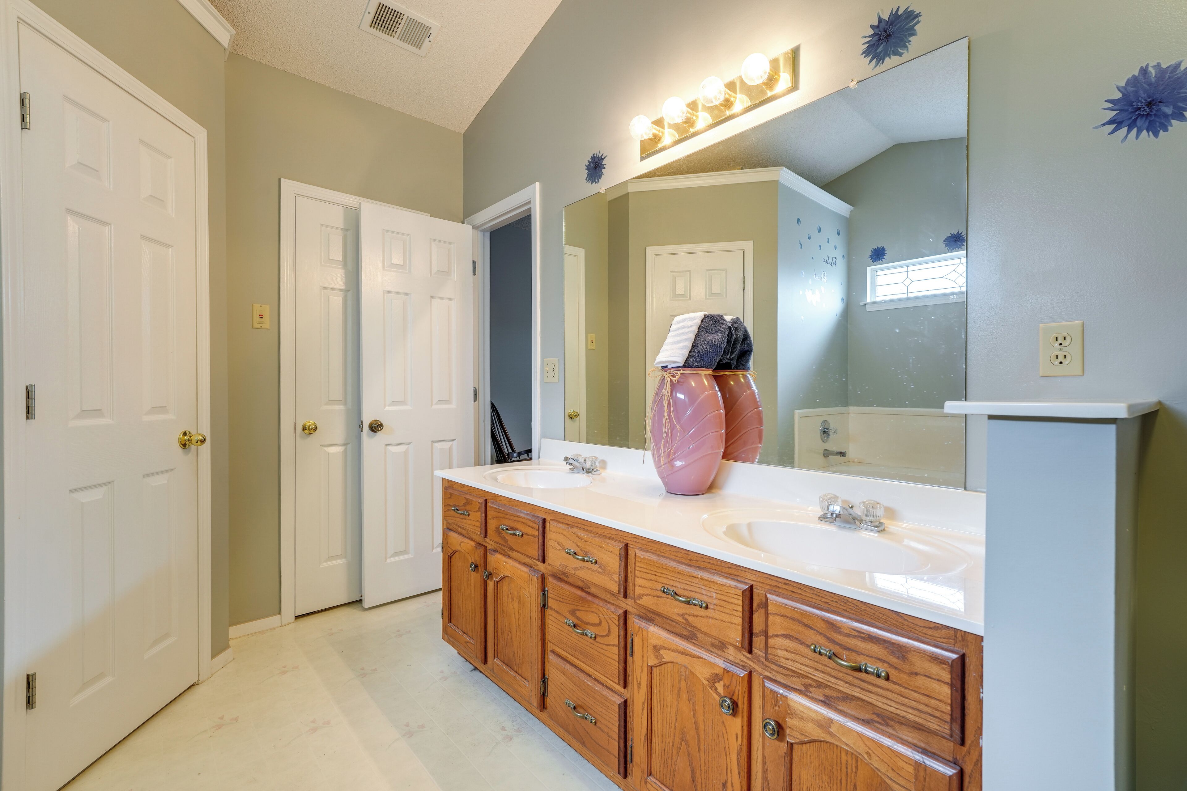 A bathroom with two sinks, wooden cabinets, a large mirror, and decorative wall stickers.