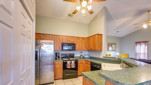 A kitchen with wooden cabinets, stainless steel appliances, a granite countertop, and a ceiling fan. - Horn Lake Home w/ Yard: 8 Mi to Graceland! (Horn Lake)