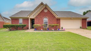 A single-story brick house with a gabled roof, a front door, and a garage. - Horn Lake Home w/ Yard: 8 Mi to Graceland! (Horn Lake)