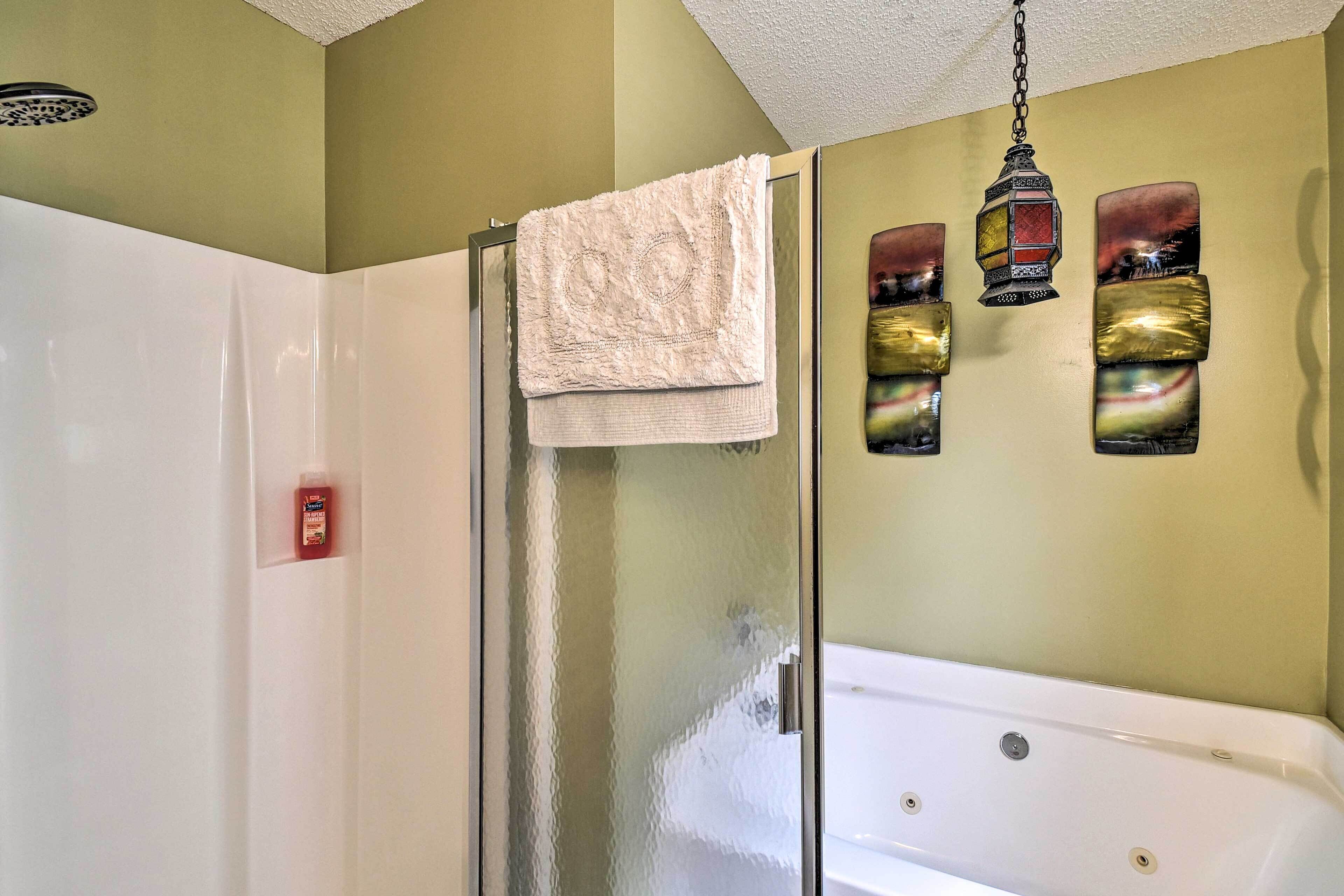 A bathroom with a glass shower enclosure, a white bathtub, and decorative wall art.