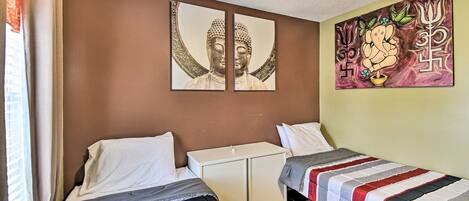 A room with two beds, a white cabinet, and a wall with religious artwork.