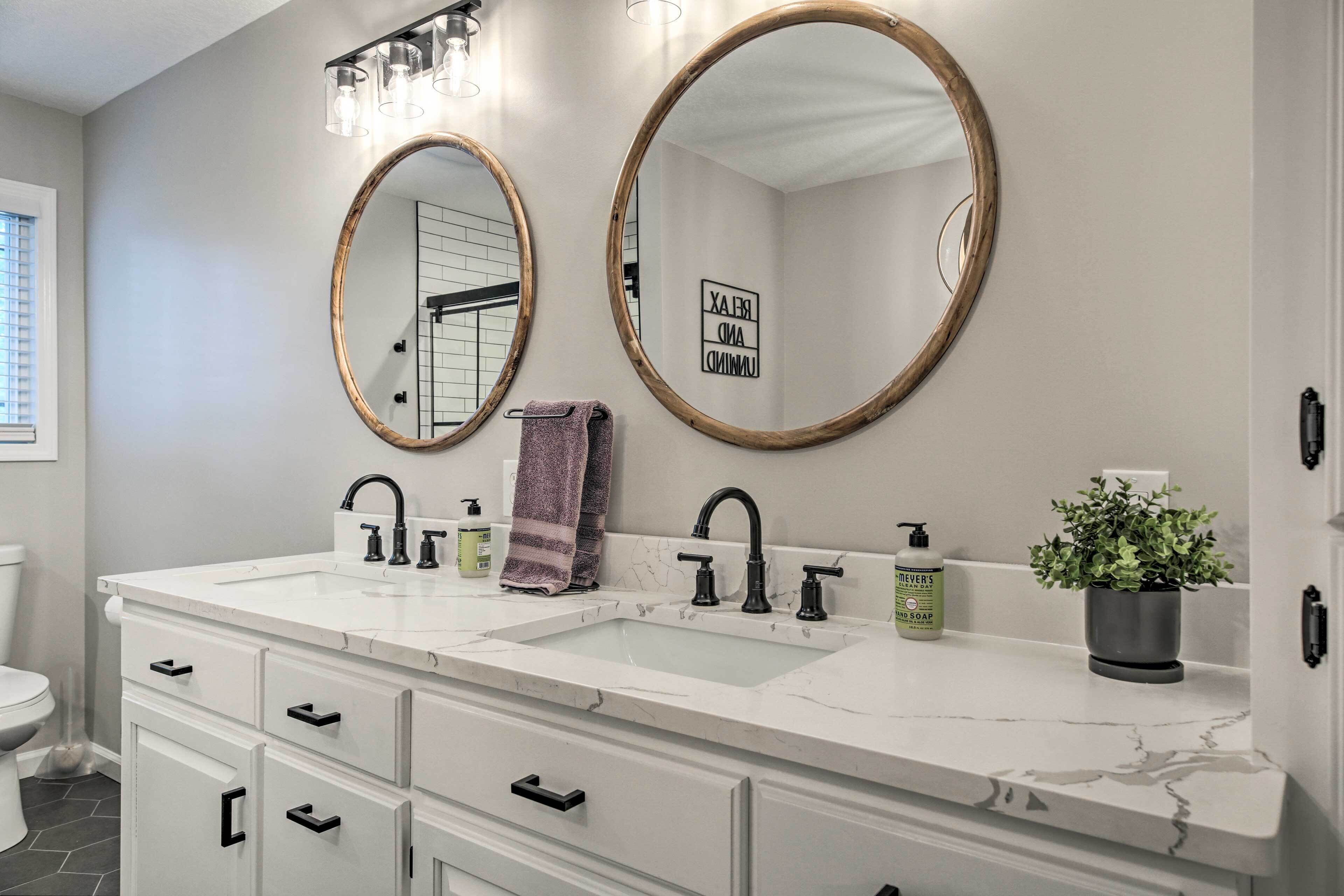 Une salle de bain avec deux lavabos, un grand miroir et un porte-serviettes.