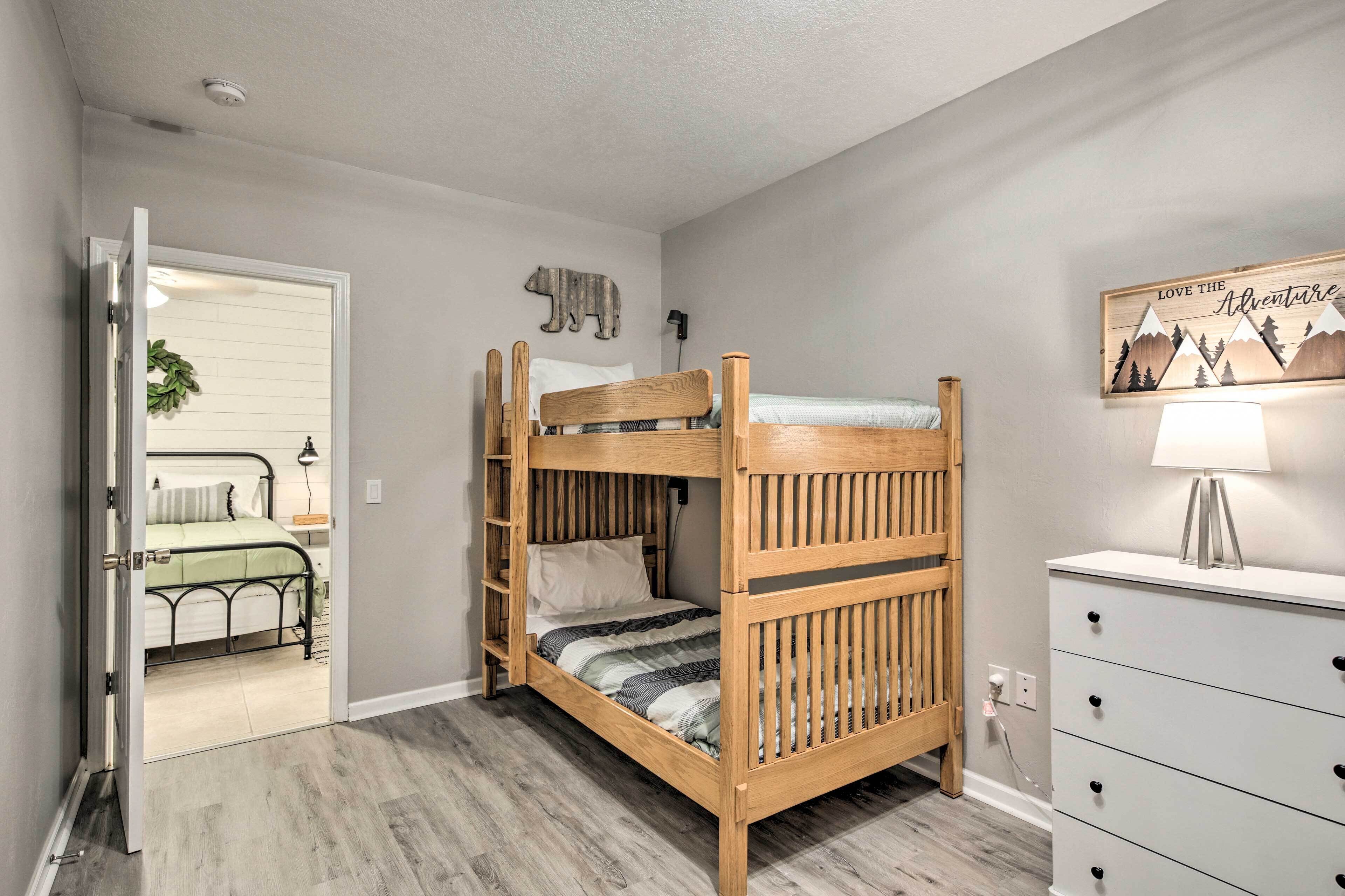 A bunk bed with a wooden frame and a white dresser with drawers.
