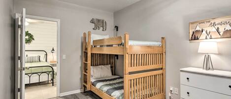 A bunk bed with a wooden frame and a white dresser with drawers.