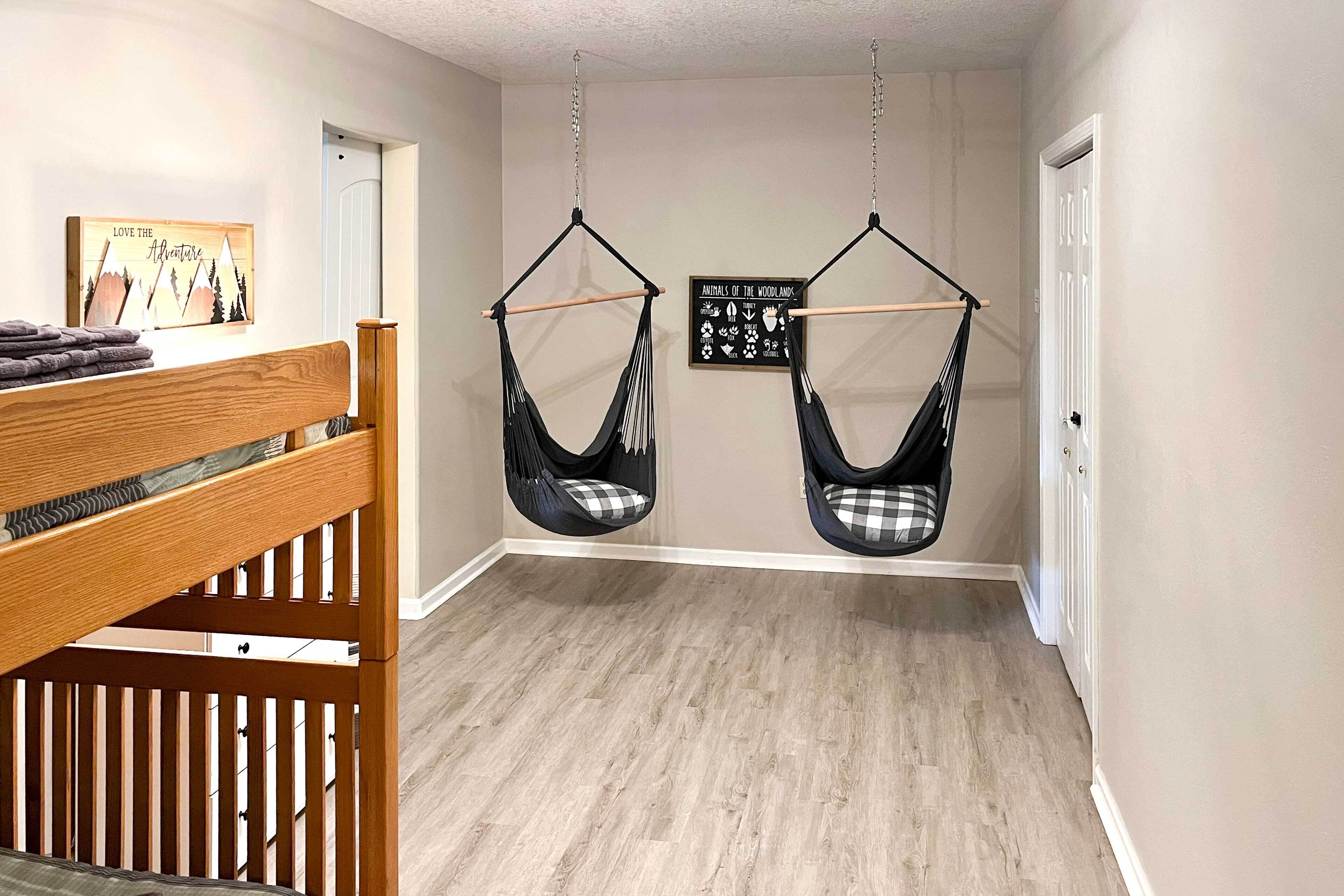 A hallway with a wooden crib, two black hammocks, a wall-mounted sign, and a door.
