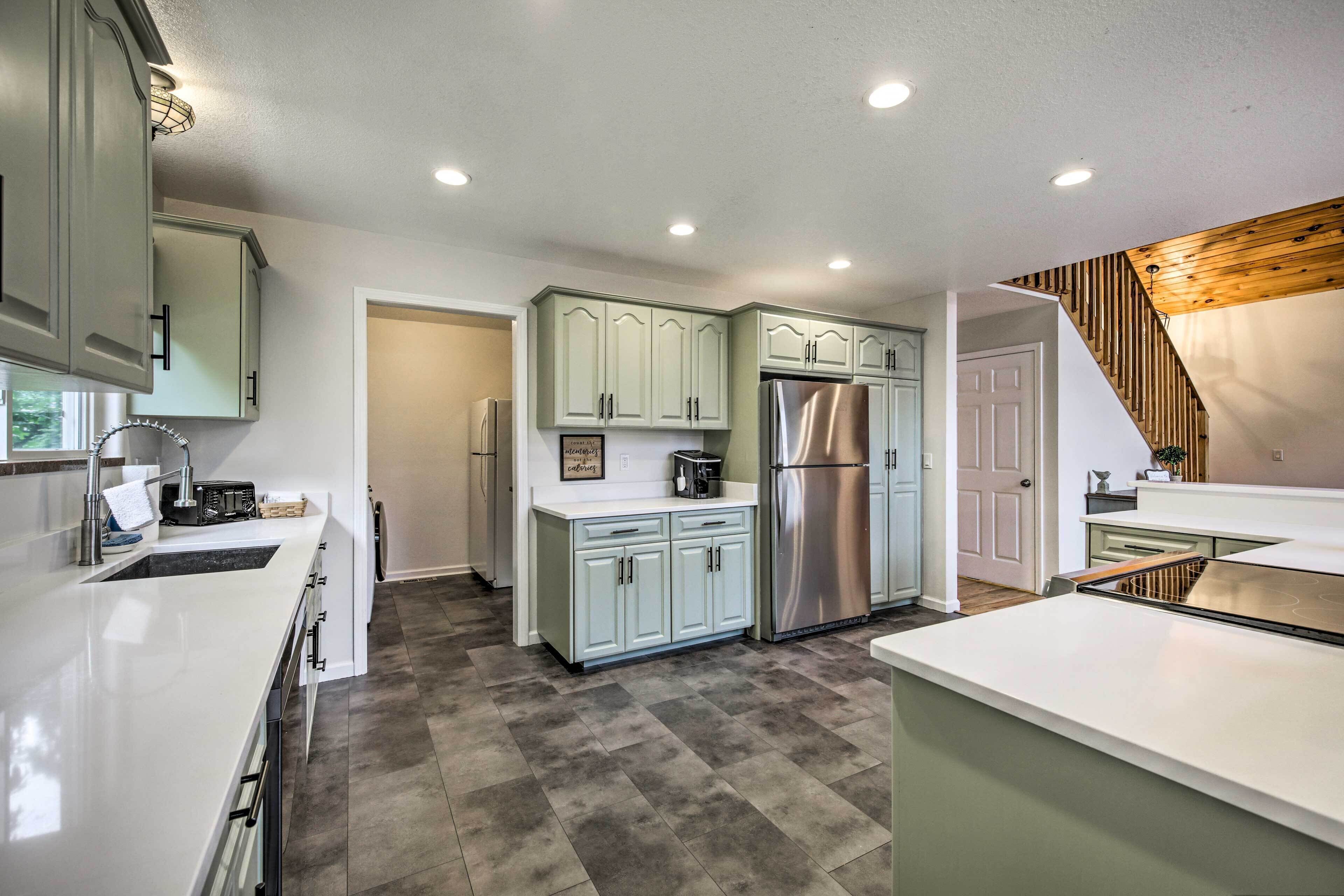 Una cocina moderna con armarios blancos, un refrigerador de acero inoxidable y una escalera de madera.