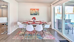 A dining area with a table set for four, white chairs, a colorful rug, and a painting on the wall. - Vibrant, Colorful Tucson Abode w/ Pool & Hot Tub (Tucson)