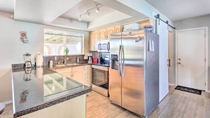 A modern kitchen with granite countertops, stainless steel appliances, and wooden cabinets. - Vibrant, Colorful Tucson Abode w/ Pool & Hot Tub (Tucson)