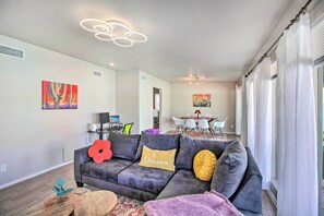 A modern living room with a gray sectional sofa, a coffee table, and a dining area with a table and chairs. - Vibrant, Colorful Tucson Abode w/ Pool & Hot Tub (Tucson)