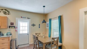 A dining area with a wooden table and chairs, a trash can, and a door with a sign above it. - Charming Darien Hideaway w/ Porch, Near Downtown! (Darien)