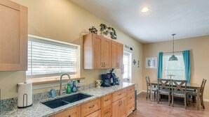 A kitchen with wooden cabinets, a granite countertop, a sink, and a dining area with a table and chairs. - Charming Darien Hideaway w/ Porch, Near Downtown! (Darien)