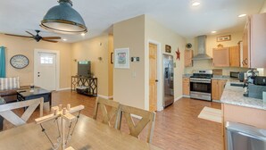 A spacious kitchen with wooden cabinets, a stainless steel refrigerator, and a dining area with a wooden table and chairs. - Charming Darien Hideaway w/ Porch, Near Downtown! (Darien)
