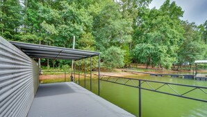 Een overdekt terras met uitzicht op een groene waterpartij en omliggende bomen.