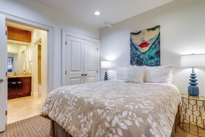 A bedroom with a large bed, a painting on the wall, and a bathroom visible through an open door. - Near Lumen Field! Walkable Dtwn Seattle Condo (Seattle)
