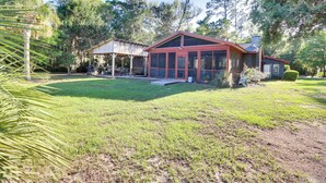 A house with a large glass front, a covered porch, and a well-maintained lawn. - Dock & Views! Waterfront Baisden's Bluff Home (Crescent)