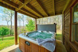 Un bain à remous en bois offrant une vue sur une zone herbeuse et des arbres.